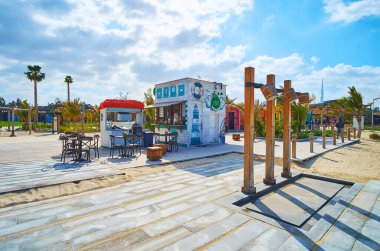 DUBAI, UAE - MARCH 4, 2020: The wooden pillars of beach shower and the small juice bar behind it, La Mer public beach, on March 4 in Dubai