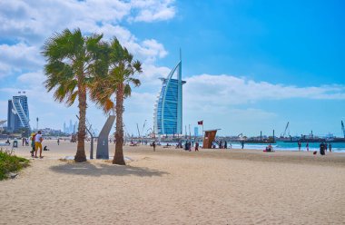 The futuristic skyline with the luxury Burj al Arab behind the public beach of Jumeirah, Dubai, UAE