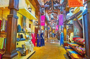 DUBAI, UAE - MARCH 4, 2020: The fashion stalls in Souk Madinat Jumeirah market with traditional dresses, scarves, pillow cases, covers , carpets, on March 4 in Dubai