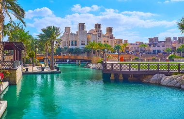 Souk Madinat Jumeirah pazarının manzarasının tadını çıkarın, Fort Island 'ı gözlemleyin, palmiyeli yeşil park, yaya köprüsü ve el değmemiş rüzgar kapanı kuleleri olan pazar binası, Dubai, BAE