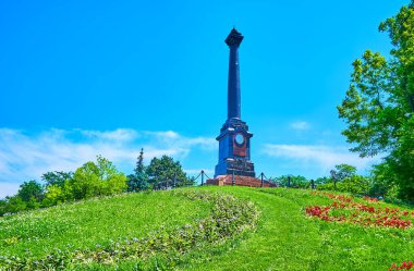 Rus İmparatoru 'nun portresiyle süslenmiş ve etrafı renkli çiçek yatakları ve çimlerle çevrili manzaralı II. Alexander Sütunu, Shevchenko Parkı, Odessa, Ukrayna