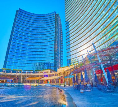 MILAN, ITALY - 9 Nisan 2022: Gae Aulenti Meydanı 'ndaki modern cam binalardaki alışveriş merkezleri, 9 Nisan' da İtalya 'nın Milano kentinde