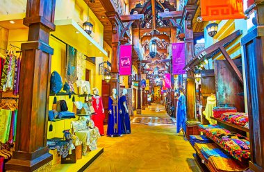 DUBAI, UAE - MARCH 4, 2020: The fashion stalls in Souk Madinat Jumeirah market with traditional dresses, scarves, pillow cases, covers , carpets, on March 4 in Dubai