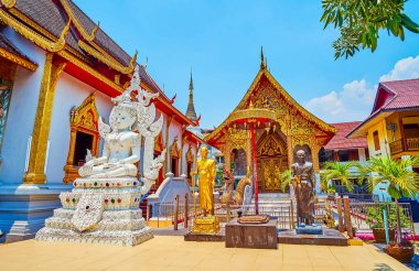 The white Buddha statue and the sculptures of bhikkhu monks in front of the Ubosot, decorated with gilt patterns, Wat Thung Yu, Chiang Mai, Thailand