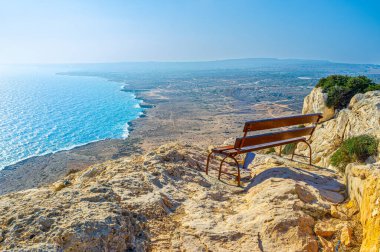 Cape Greco 'daki bir tepenin kenarında kıvrımlı kıyı şeridi ve turkuaz deniz manzarası sunan bir bank, Kıbrıs Rum Kesimi Ayia Napa