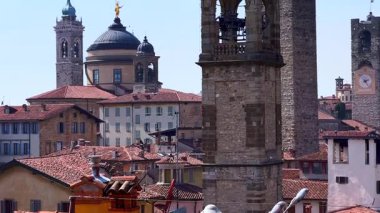 Ortaçağ şehir kuleleri ve fayans çatılarının dikey manzarası San Pancrazy Kilisesi 'nin oyulmuş çan kulesi, Palazzo della Podesta' nın saat kulesi, Bergamo Katedrali 'nin kubbeleri ve Belfries ve İtalya' nın Santa Maria Maggiore Bazilikası.