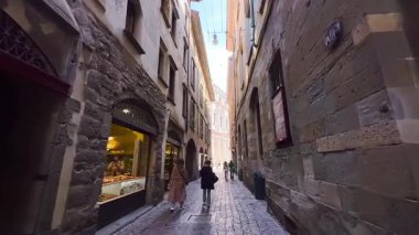İtalya, Bergamo 'daki Via Bartolomeo Colleoni' deki eski kasaba evleri, kafeler, dükkanlar ve turist tezgahları boyunca yürü.