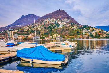 Lugano, İsviçre 'de tekne ve alp manzaralı liman sahnesi