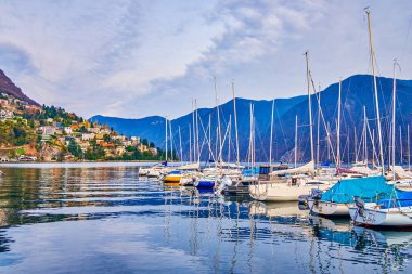 Lugano, İsviçre 'de tekne ve alp manzaralı liman sahnesi