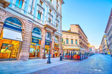 MILAN, İTALYA - 5 Nisan 2022: 5 Nisan 'da İtalya' nın Milano kentinde mağazaların, butiklerin ve açık hava restoranlarının sayısız parlak penceresinden geçerek Dante boyunca keyifli bir akşam yürüyüşü