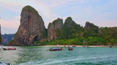 Tekne, Railay Yarımadası 'ndaki Phra Nang Sahili' nde (Rai Leh) tropik bitki örtüsüyle kaplı keskin kayalarla yüzer.