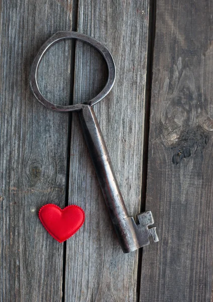 Wielki klucz i czerwonym sercem na drewnianym stole rustykalne — Zdjęcie stockowe