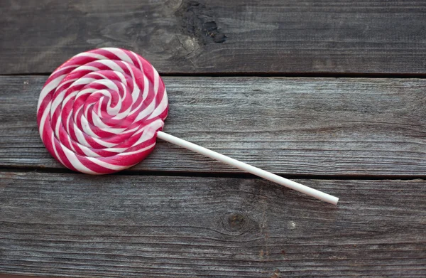 Röda och vita söta lollipop på träbord — Stockfoto