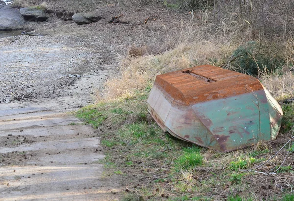 Старая металлическая лодка на берегу пруда — стоковое фото
