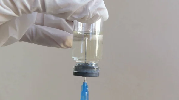 Doktor şeffaf bir ampulden şırıngaya aşı çekiyor. Virüs aşısı yakın plan.