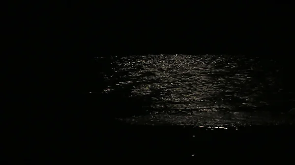 Gecenin bir yarısı nehir kıyısında ay ışığı yolu. Ayın suyun üzerindeki yansıması..