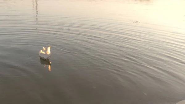 La barca di carta galleggia lungo il fiume e brucia. Origami di carta. — Foto Stock