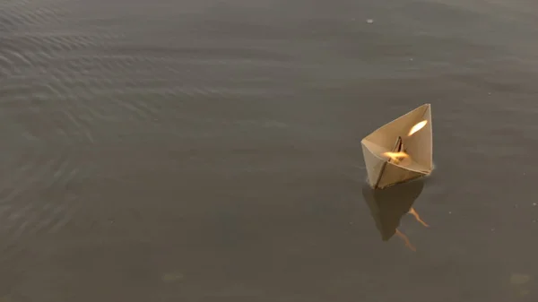 O barco de papel flutua rio abaixo e arde. Origami de papel. — Fotografia de Stock