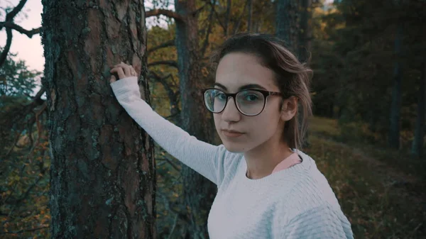 Uma jovem com óculos fica no penhasco e olha para as montanhas verdes. Vista pelas traseiras. Viaje pelas montanhas. — Fotografia de Stock