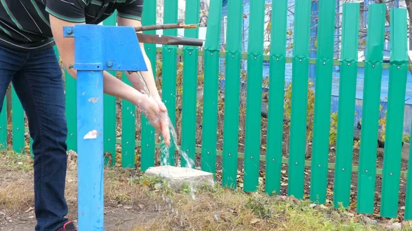 Un joven se lava las manos con una columna de agua. Antiguo hidrante ruso. — Foto de Stock