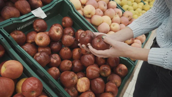 Une jeune femme cueille des pommes rouges au marché. Les filles mains gros plan. — Photo