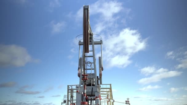 En oljerigg extraherar råvaror från marken mot bakgrund av himlen. — Stockvideo