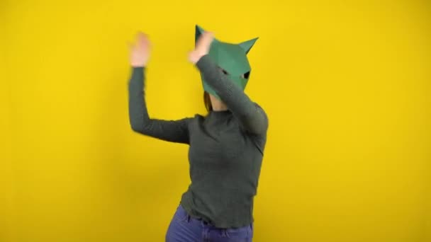 Jeune femme dans un masque chacal en carton danse sur un fond jaune. Femme dans un pull vert et masque. — Video