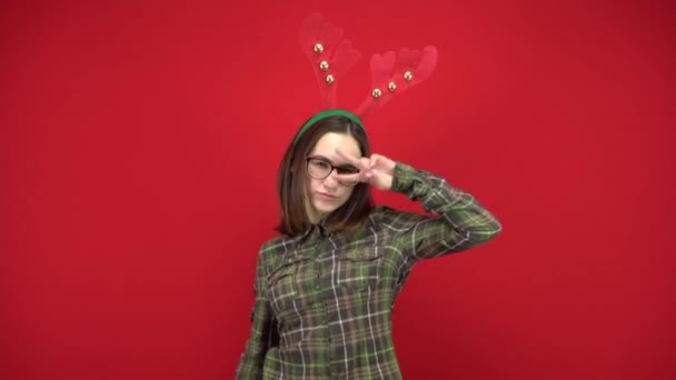 Une jeune femme danse avec un bandeau en forme de bois de Noël. Studio tournage sur fond rouge. — Video