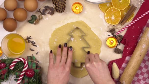 젊은 여성이 전통적 인 크리스마스 트리 쿠키를 만든다. 반죽 속에 인형을 넣는다. 위에서 바라본 경관. — 비디오