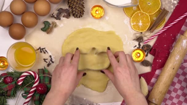 Une jeune femme fait un biscuit de Noël traditionnel sous la forme d'une mitaine. Une figuru est placée dans la pâte. Vue d'en haut. — Video