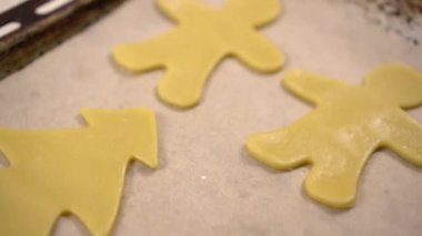 Farklı şekillerde pişirilmemiş kurabiye hamuru bir yemek tepsisinin üzerinde. Kamera hareket ediyor..