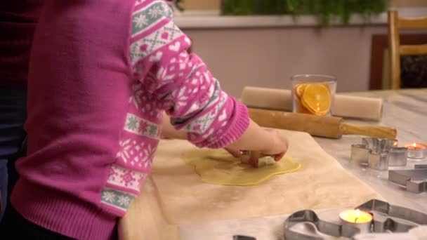 Una hija con una madre joven hace galletas de jengibre de Navidad en forma de estrellas. Una estatuilla se coloca en la masa. — Vídeos de Stock