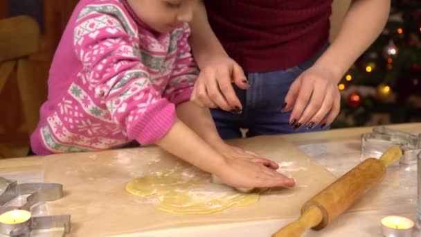 Una figlia con una giovane madre fa i tradizionali biscotti di Natale festivi sotto forma di umani. Una statuetta è posta nell'impasto. — Video Stock