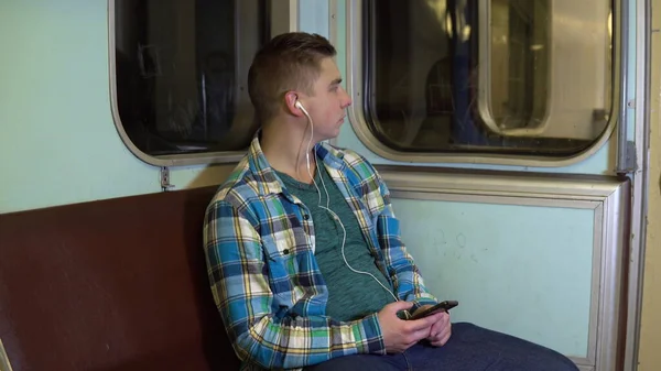 Um jovem ouve música em fones de ouvido em um trem de metrô. Velho carro de metrô — Fotografia de Stock