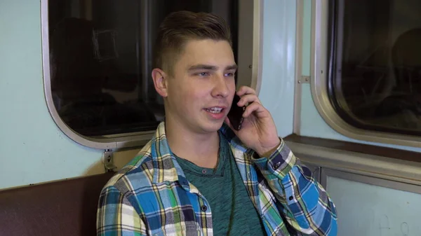 Seorang pemuda berbicara di telepon di kereta bawah tanah. Old kereta bawah tanah — Stok Foto