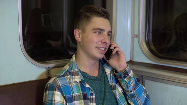 Молодой человек говорит по телефону в поезде метро. Старый вагон метро — стоковое фото