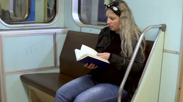 Una mujer embarazada está leyendo un libro en un tren subterráneo. Antiguo vagón de tren del metro —  Fotos de Stock