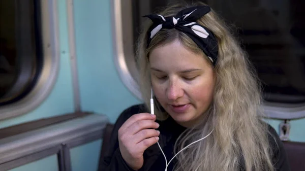 Uma mulher grávida está falando ao telefone através de fones de ouvido para um trem de metrô. Carro velho do trem do metrô — Fotografia de Stock