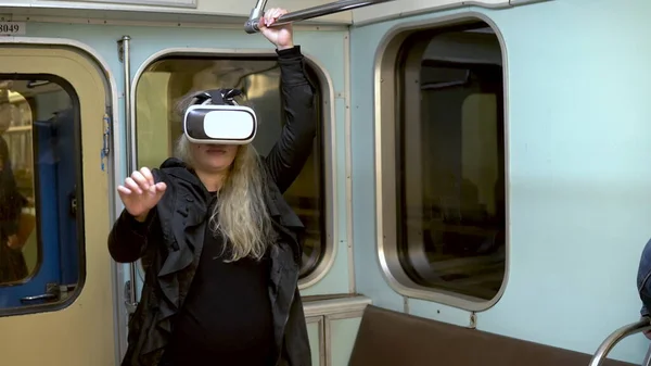 Ciężarna kobieta w kasku wirtualnej rzeczywistości w pociągu metra. Stary wagon metra — Zdjęcie stockowe