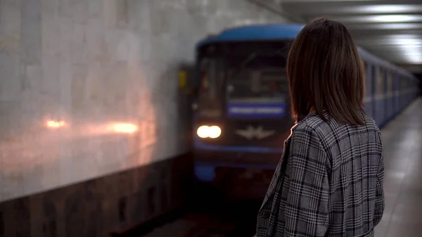Eine junge Frau nähert sich in der U-Bahn dem Zug. ein Mädchen in Mantel und Brille — Stockfoto