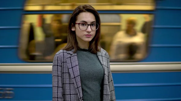 Une jeune femme se tient dans le métro. En arrière-plan un train monte — Photo