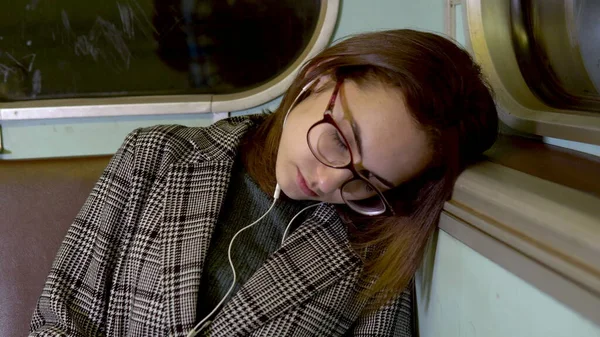 Una joven se quedó dormida en un tren subterráneo. Chica con auriculares en los oídos. Viejo vagón de metro —  Fotos de Stock