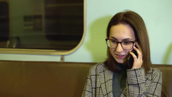 A young woman speaks on the phone in a subway train. Old subway car