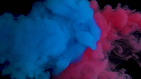 Pintura real azul y roja en agua. Tinta arremolinándose bajo el agua. Nube de colisión de tinta aislada sobre fondo negro. Vista de cerca. — Foto de Stock