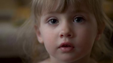 Küçük kız kameraya yakından bakıyor.