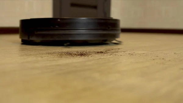 La aspiradora robot está limpiando la habitación. Una aspiradora redonda conduce automáticamente alrededor de la casa y limpia la suciedad — Foto de Stock