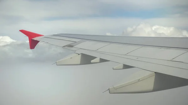 Das Flugzeug fliegt in weißen Wolken. Blick aus dem Flugzeugfenster auf den Flügel — Stockfoto