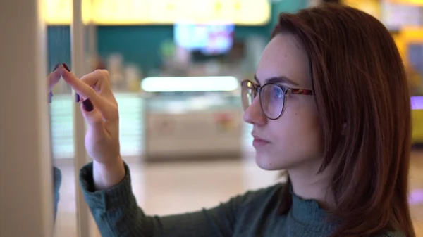 Une jeune femme commande de la nourriture au terminal tactile d'un centre commercial. Technologie moderne. Sur le terrain de restauration sans faire la queue. Gros plan — Photo