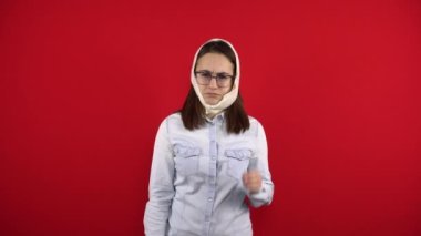 Gözlüklü genç bir kadının dişindeki ağrıdan dolayı başı geriye sarılmış. Kız eliyle yanağına dokunuyor. Kırmızı arkaplanda çekim.