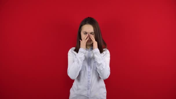 La joven tiene dolor de nariz, la toca con la mano. Disparos sobre un fondo rojo. — Vídeo de stock